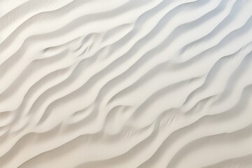  a close up of a white sand dune with wavy lines in the sand and a blue sky in the background.