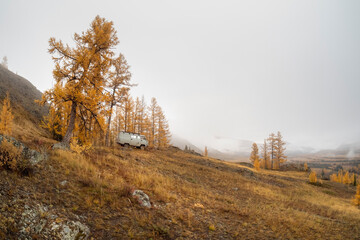 Traveling in the autumn mountains by car. Car on forest trail, from the side view.