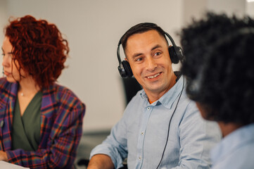 Middle aged handsome call operator wearing headset and talking with clients