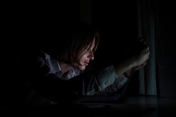 Side view of young tired businesswoman working on laptop at night. Work from home concept