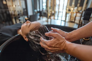 Tableaux sur verre Salon de massage Asian woman lying down on salon washing bed getting hair washed in hair salon by stylist, Hairdresser shampoo the customer hair then washing hair