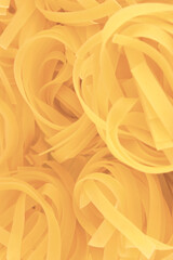 Traditional fettuccine ribbons pattern background, large detailed vertical raw dry long uncooked egg pasta macro closeup, natural golden texture diminishing perspective - 715927629