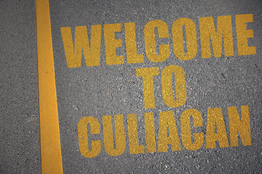 asphalt road with text welcome to Culiacan near yellow line.