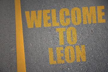 asphalt road with text welcome to Leon near yellow line.