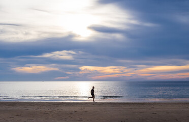 Fototapeta na wymiar Landscape horizon panorama summer look man person run jogging exercise on sea sand beach wind wave cool holiday calm sunset sky evening day time calm nature tropical beautiful ocean water travel