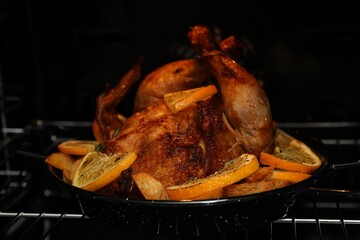 Chicken with orange slices baking in oven