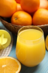 Freshly made juice, oranges and reamer on blue table