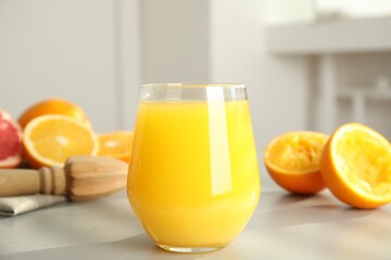 Freshly made juice, oranges and reamer on table, closeup