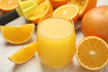 Freshly made juice, oranges and reamer on wooden table, closeup