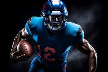 Portrait of American football player running with the ball. Muscular African American athlete in a blue and red uniform with an ovoid ball in a dynamic pose. Isolated on black background.