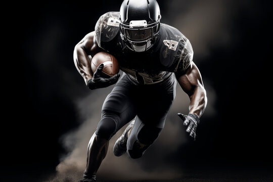 Portrait of American football player running with the ball. Muscular African American athlete in a black and white uniform with an ovoid ball in a dynamic pose. Isolated on black background.