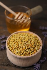 Fresh bee pollen granules in bowl, lavender and honey on wooden table, closeup