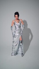 Glamorous model poses in the studio in a silver dress
