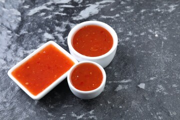 Spicy chili sauce on black textured table, space for text