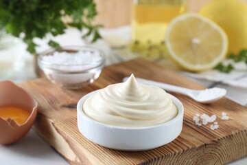 Fresh mayonnaise sauce in bowl and ingredients on table
