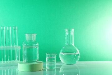 Laboratory analysis. Different glassware on table against green background, space for text