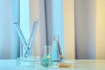 Laboratory analysis. Different glassware on table against color background, space for text