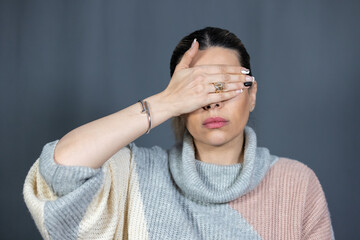 Portrait of an oriental woman covering her eyes with her hands