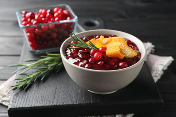 Fresh cranberry sauce, rosemary and orange peel in bowl on table, closeup