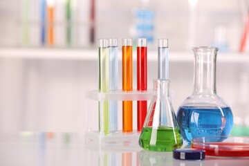 Laboratory analysis. Different glassware with liquids on white table against blurred background. Space for text