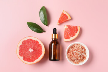 Flat lay composition with grapefruit essential oil on pink background