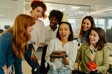 Chinese woman blowing out a candle on cake while celebrating birthday at work