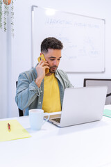 A concentrated male professional engages in a business call, surrounded by office essentials,...