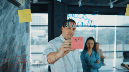 Skilled businessman presents marketing idea to project manager by using colorful sticky notes at...