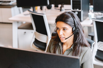 Dedicated female customer support representative with headset at a workstation. 