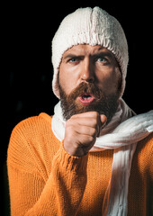 Bearded sick man in sweater, hat and scarf coughing. Handsome guy having sore throat and coughing...