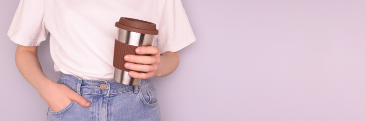 Banner with woman hold in hands reusable coffee cup in front of blue background.