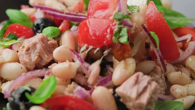 Eating White bean tuna salad with olive, red onion, tomatoes. Healthy food.