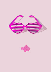 Pink eyeglasses and glitter fish shape lips on pastel pink background. Silhouette of face. Flat lay. Minimal surreal concept. 