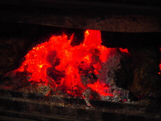 Reddish embers and bright orange flames in the winter bonfire.