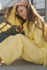 cute smiling female in a yellow summer outfit sitting outdoors