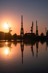 Silhouettes of cranes in the shipyard during sunrise