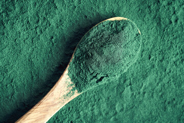 Green spirulina powder on a spoon - healthy nutritional supplement