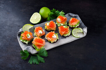 Traditionelle Pumpernickel Taler mit Räucherlachs und Kaviar serviert als Häppchen auch einem Design Teller mit Textfreiraum