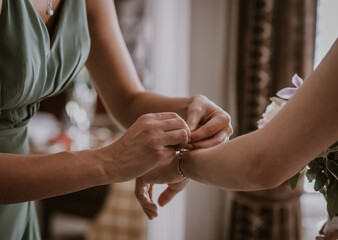 Bridesmaid or woman putting on  bracelt on to brides wrist close up - Powered by Adobe