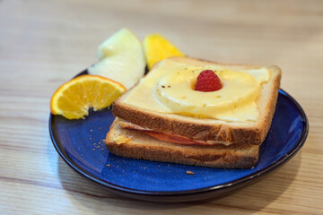 Toast Hawaii, broiled open sandwich with ham, pineapple and cheese, a few pieces of fruit and...