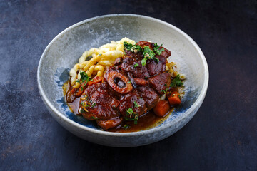 Traditionelles geschmortes italienisches Ossobuco alla Milanese mit Gremolata und Spätzle serviert in einer Nordic Design Schale