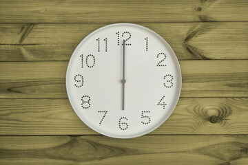 Six o'clock. Time management or business concept. Plain white wall clock showing 6 pm on a wooden background. End of working day. Opening or closing hours. Schedule or working, study hours.