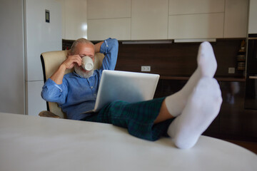 Serious mature older man client sits on couch in room talking on video call using laptop complain...