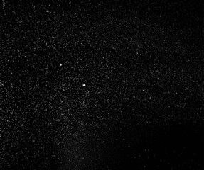Freezing falling snowflakes or stardust in air on black background for overlay blending mode. Stopping the movement of white powder on a dark background, selective focus
