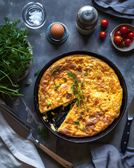 Tasty pie in the pan on the table with eggs, tomatoes and other vegetables. 