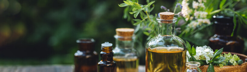 Natural organic essential oil in small glass bottles on wooden background. Homemade production for spa, sauna, bath. Relaxation, alternative medicine, remedy, naturopathy, pure ingredients