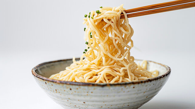 A minimalist composition featuring a pair of elegant chopsticks delicately lifting a tangle of savory Chinese noodles from a porcelain bowl. The simplicity of the image highlights