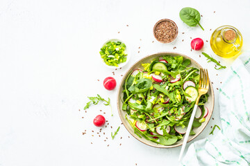 Green salad with spinach, arugula and radish with olive oil. Top view on white.