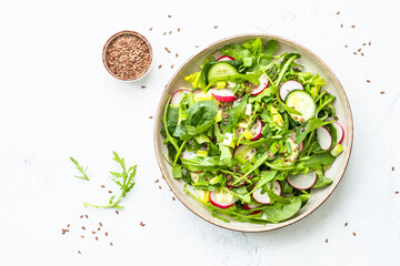 Green salad with spinach, arugula and radish with olive oil. Top view on white.