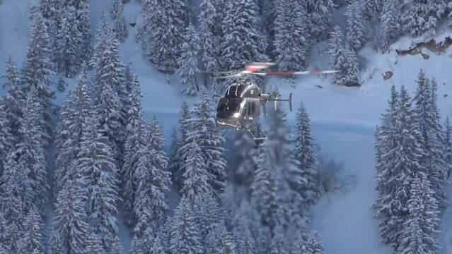 A black helicopter at the background blue sky is landing in snow mountains